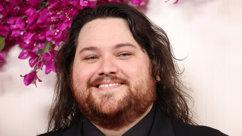 Wolfgang Van Halen posing in front of purple flowers