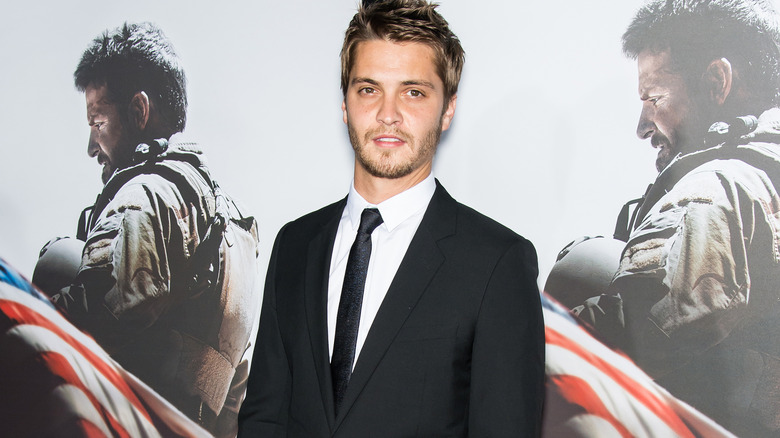 Luke Grimes poses in front of the "American Sniper" poster