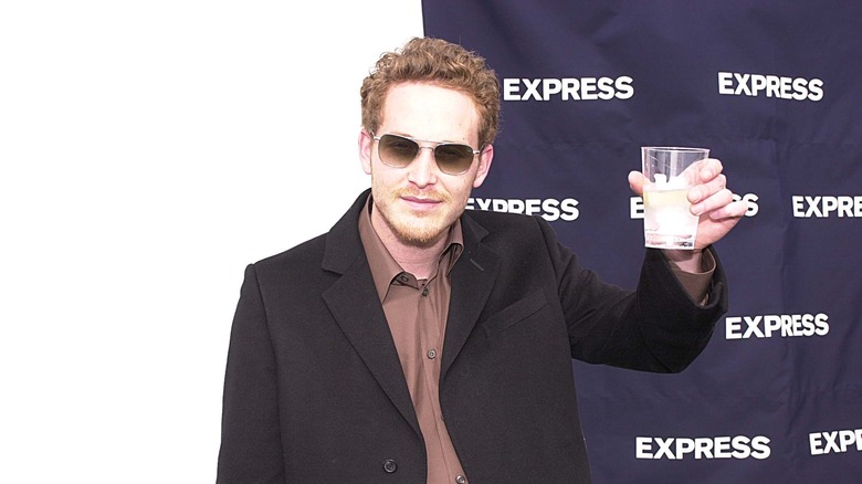 Cole Hauser holding up a drink while posing on step-and-repeat