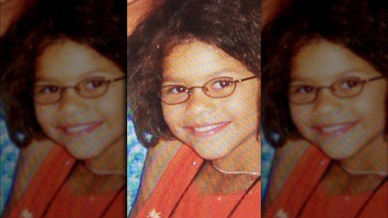 Zendaya as a kid smiling and wearing glasses.
