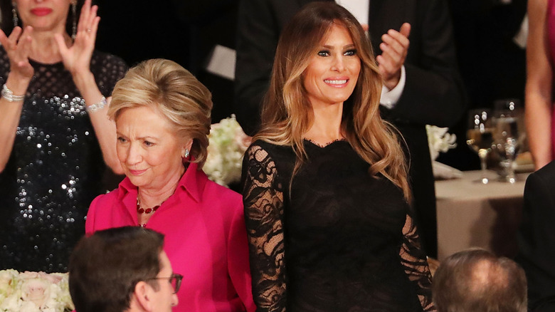 Hillary Clinton and Melania Trump standing next to each other at an event not looking at each other