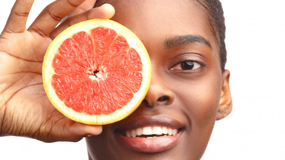 Woman holding a grapefruit in front of her face