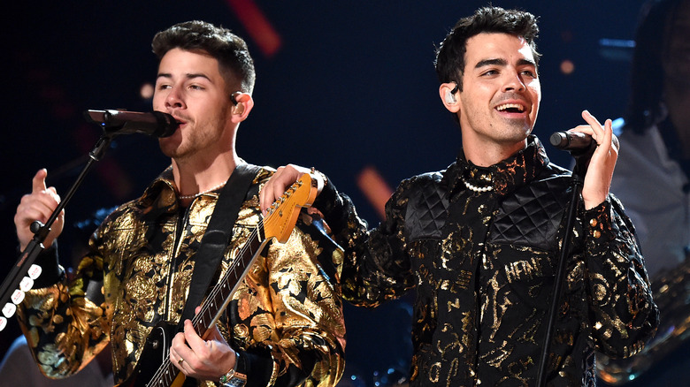 Nick and Joe Jonas wearing pearl necklaces during performance at the Grammy Awards