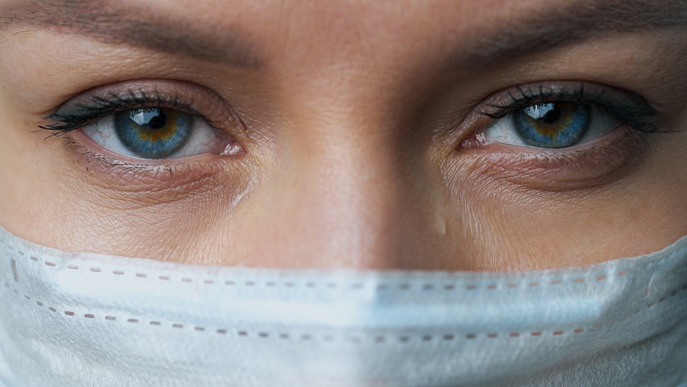 Woman wearing mask, eyes tearing