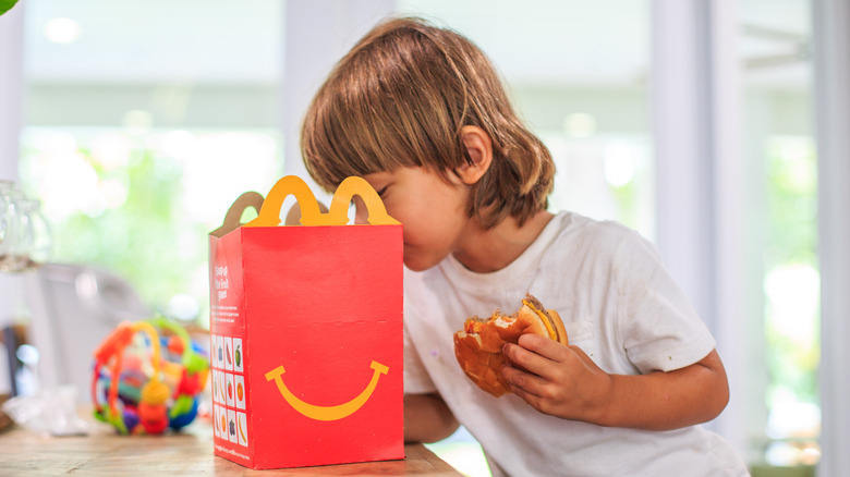 young boy looking into a happy meal box from McDonalds