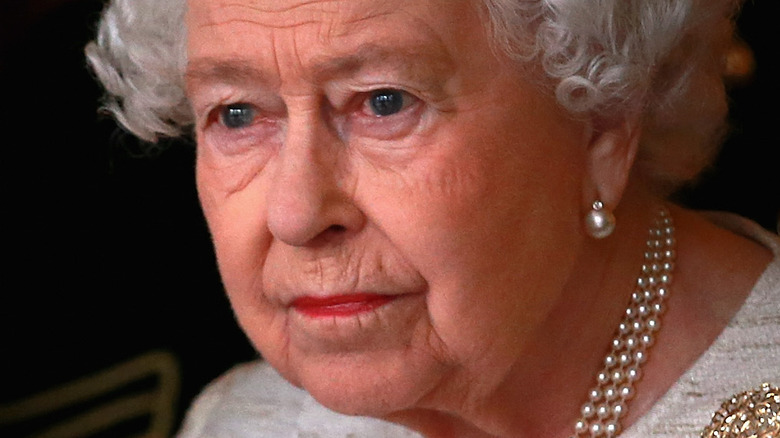 Queen Elizabeth II with serious expression and pearls