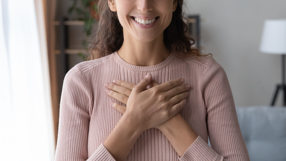 Smiling woman with her hands on her chest