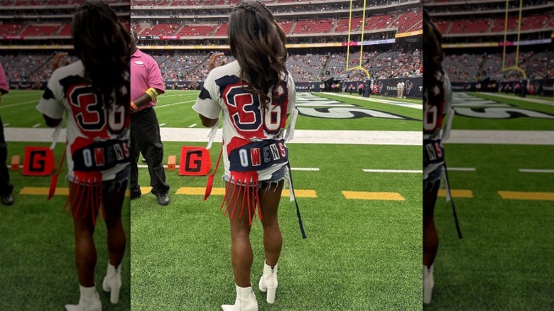 Simone Biles posing on a football field with a tasseled tee shirt