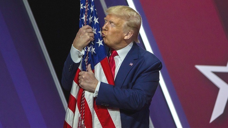 Donald Trump hugging and kissing an American flag.