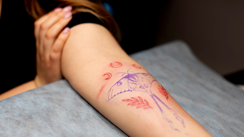 Woman getting detailed tattoo