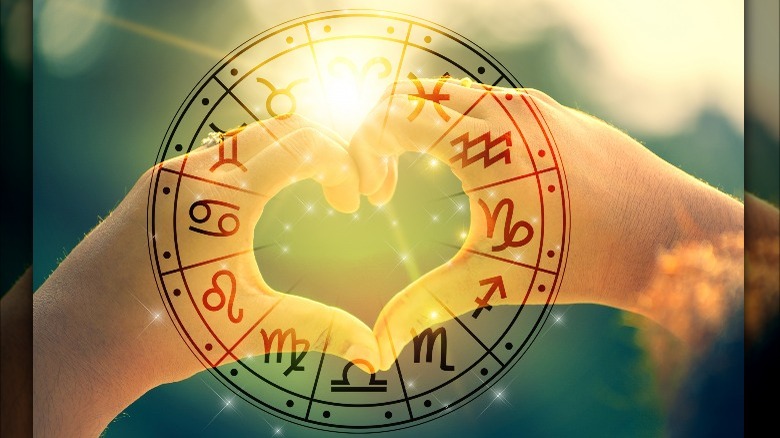 Hands forming a heart behind the zodiac wheel