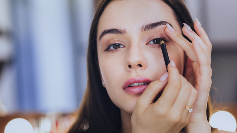 woman applying eyeliner 