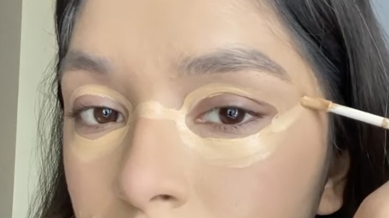 Screenshot of young woman trying the eyeglass concealer hack