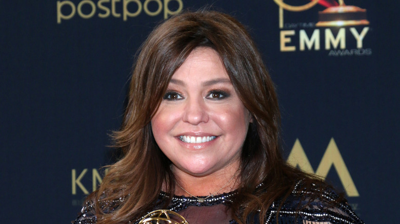 Rachael Ray smiling with an Emmy in a sparkly black dress