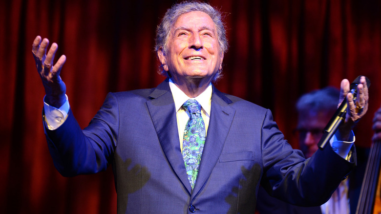 Tony Bennet raising his arms and holding a microphone
