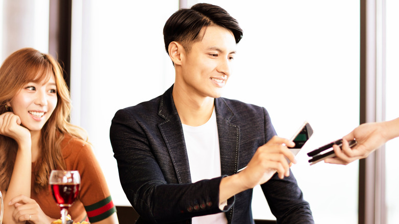 man paying for dinner for woman and himself