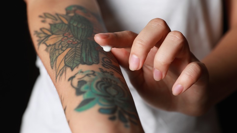Woman applying cream on tattoo