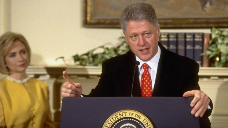 Hillary Clinton behind Bill Clinton at a press conference
