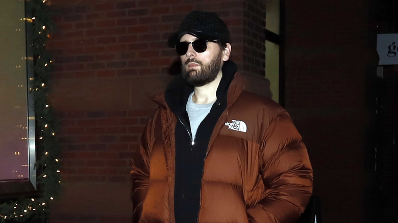 Scott Disick walking outside at night in a ballcap, sunglasses, and puffer jacket in December 2025