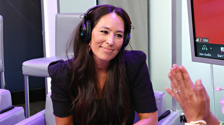Joanna Gaines smiling while wearing headphones in July 2021