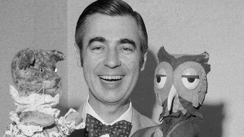 Mr. Rogers smiling with a couple of his puppets