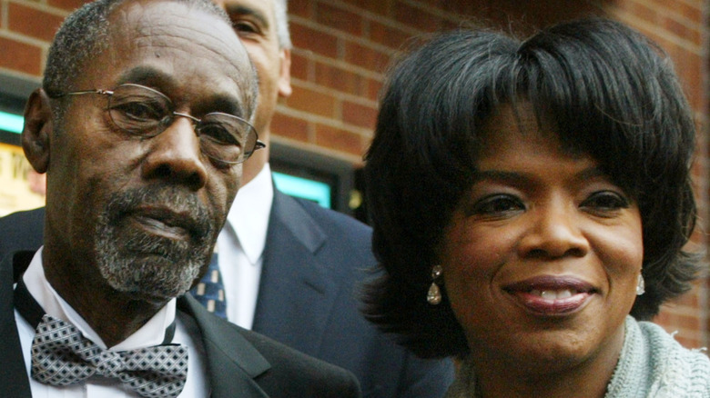 Oprah Winfrey and her father Vernon Winfrey standing outside a brick building