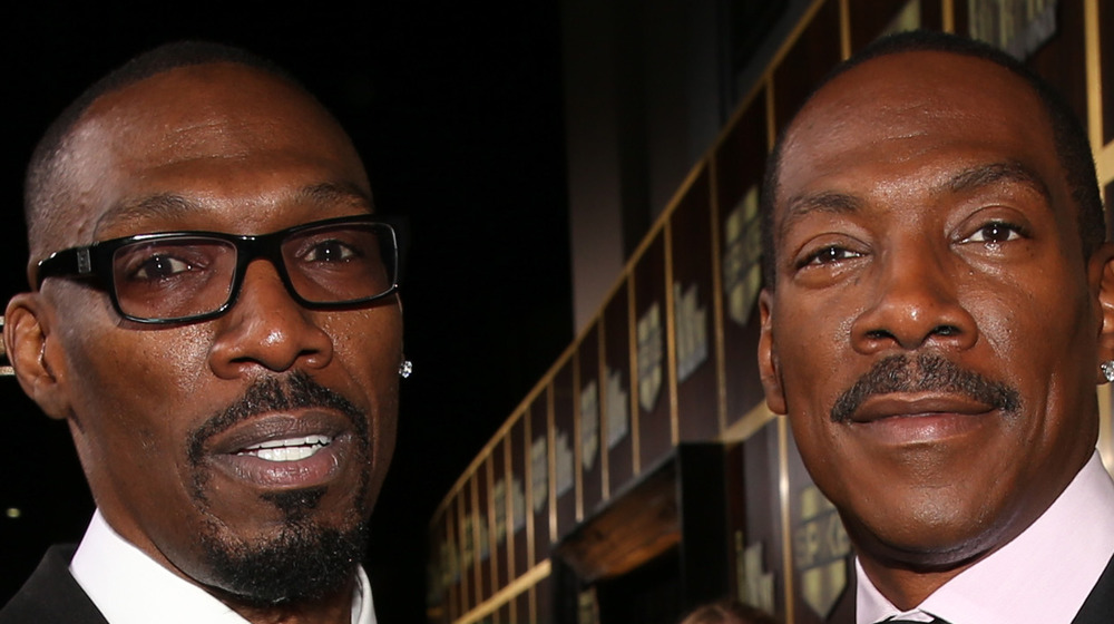 Charlie Murphy in glasses and Eddie Murphy grinning on the red carpet 