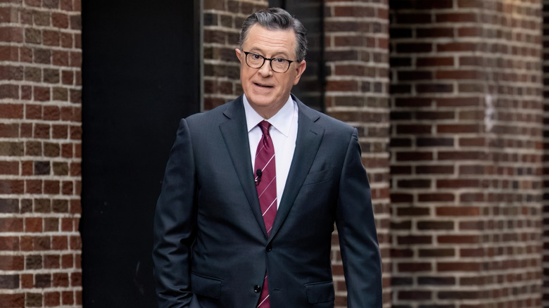 Stephen Colbert walking outside in suit