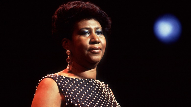 A photo of Aretha Franklin as she performs on stage under a bright light