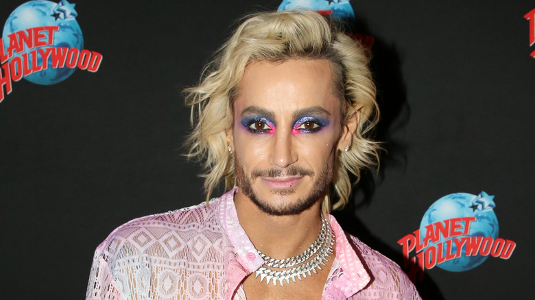 Frankie Grande with blue and pink makeup in a pink lace top with layers of necklaces.