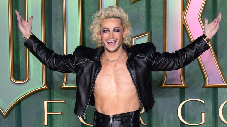 Frankie Grande with a wide smile and his arms spread out to the side, shirtless.