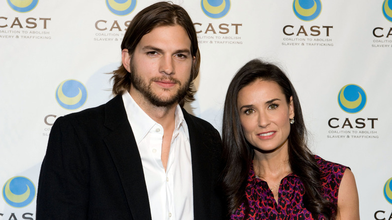 Ashton Kutcher posing at an event with Demi Moore