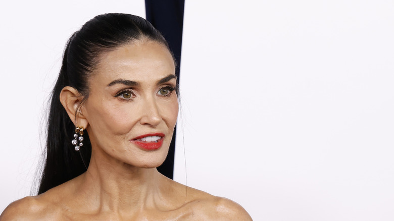 Demi Moore posing for cameras on the red carpet with her hair half-up and a bold red lip
