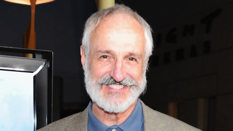 "Family Ties" actor Michael Gross smiles with a beard and mustache wearing a collared blue button up shirt