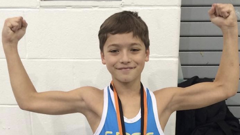 Joaquin Consuelos flexing his arm muscles as a child after a wrestling match