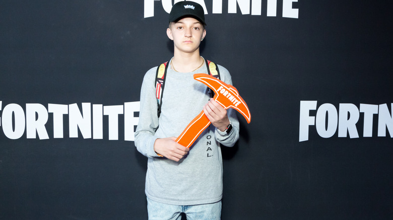 Russell Horning holding a Fortnite pickaxe on a Fortnite event red carpet 2018