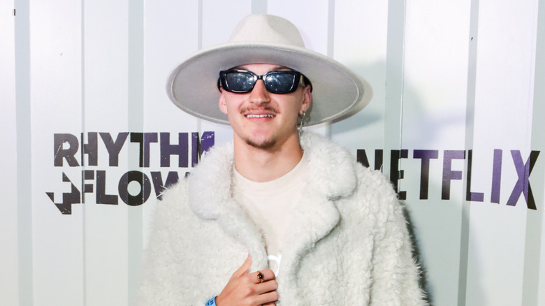 Russell Horning wearing shades and a hat with a fur coat on the red carpet in 2024