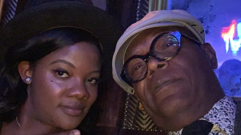 Samuel L. Jackson poses in a cap for a selfie with his daughter Zoe against a dark background