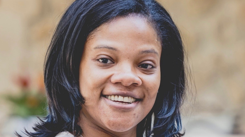 Samuel L. Jackson's daughter Zoe smiles outside with short hair and no makeup