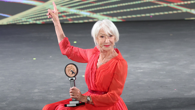 Helen Mirren holding an award and pointing upward