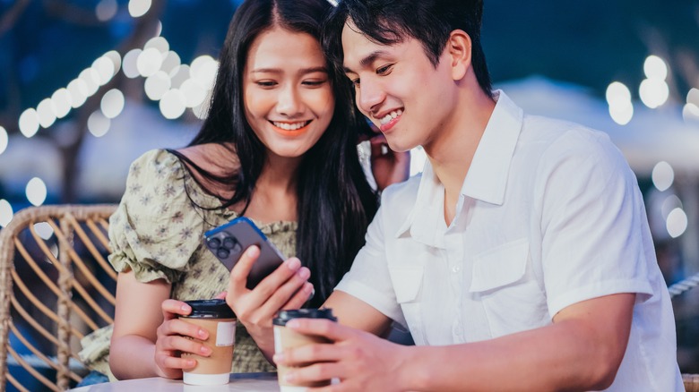 couple drinking coffee looking at phone