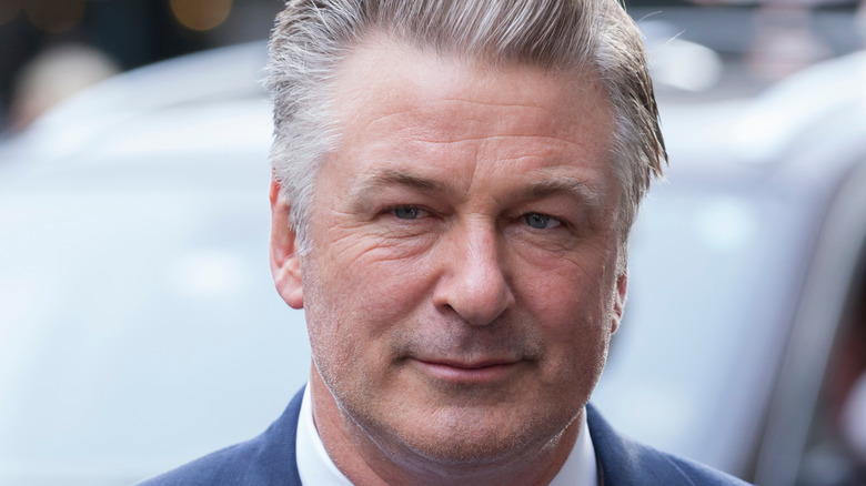 Alec Baldwin gives a slight smile with his gray hair slicked back.