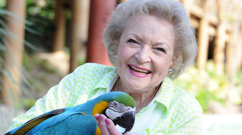 Betty White smiling with a parrot