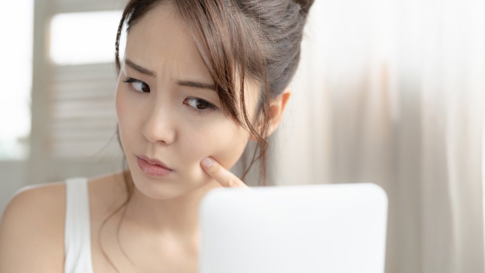 Woman looking in the mirror at blackheads