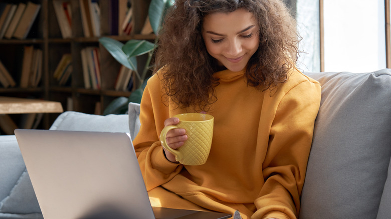 Woman working while holding a mug of coffee