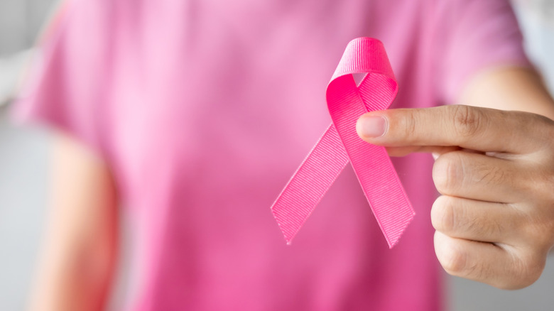 A person wearing pink and holding a pink ribbon 