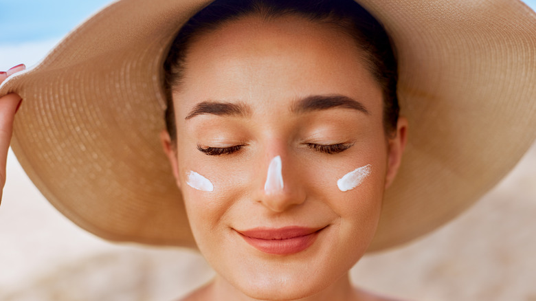 Woman in hat with sunscreen dabs