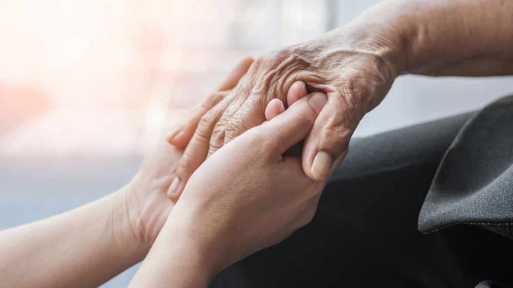 Younger hands holding wrinkled hands