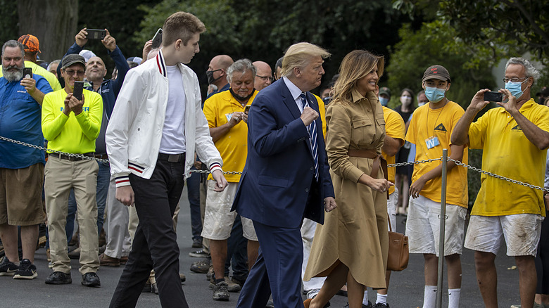 Barron, Donald, and Melania Trump walking outside among crowd