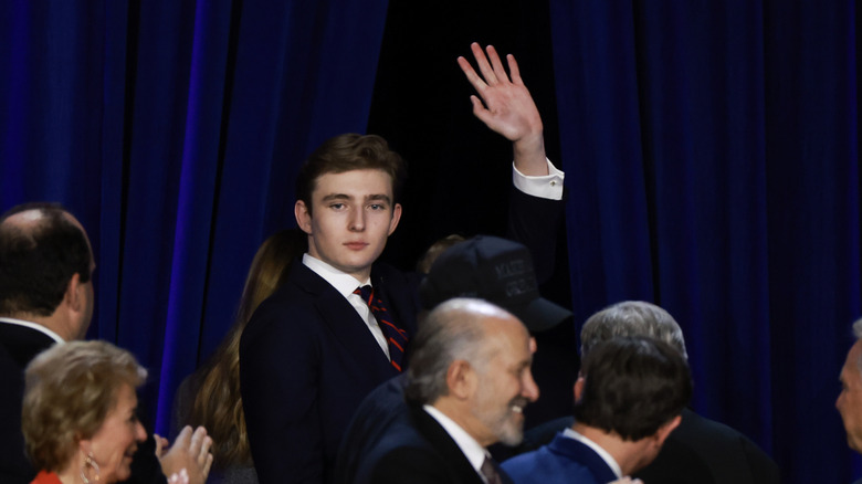 Barron Trump waving on stage surrounded by crowd